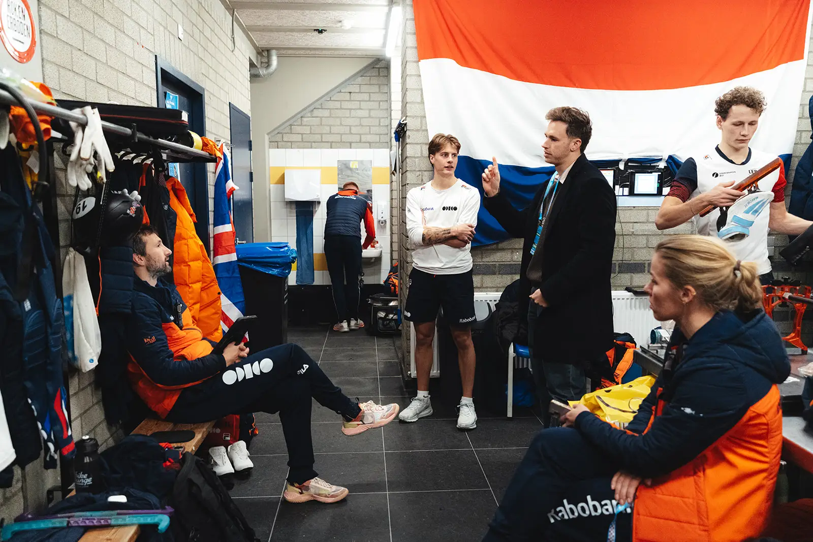 Nu doceert Harrie, terwijl Jens, de bondscoach en teammanager Geeske aandachtig luisteren.