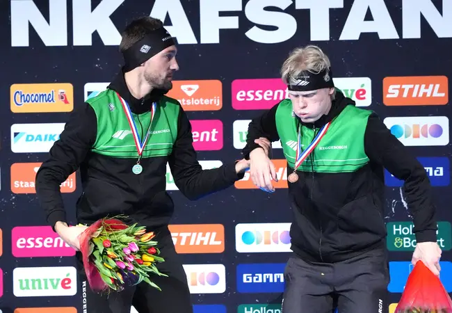 Winnaar Kjeld Nuis helpt bronzenmedaillewinnaar Tim Prins na de huldiging